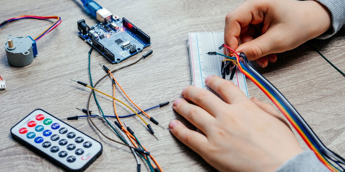 Χέρια παιδιού συνδέουν καλώδια σε πλακέτα σύνδεσης