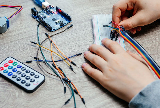 Χέρια παιδιού συνδέουν καλώδια σε πλακέτα σύνδεσης