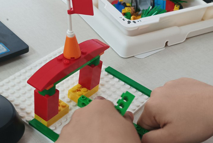Χέρια νηπίου που κατασκευάζει πόρτα με τουβλάκια Lego